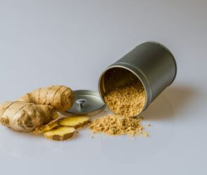 A cup of ginger and some ginger powder about to be used as part of a weight loss recipe for making ginger shots.