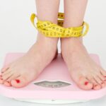 Someone standing on the scales getting confused about how they should be measuring their weight loss.
