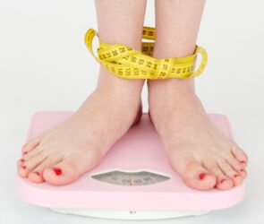 Someone standing on the scales getting confused about how they should be measuring their weight loss.
