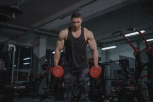 A muscular man holding a pair of red dumbells.